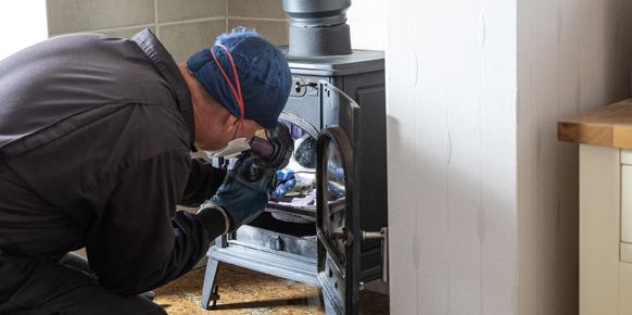 Chimney sweep inspecting a log burner